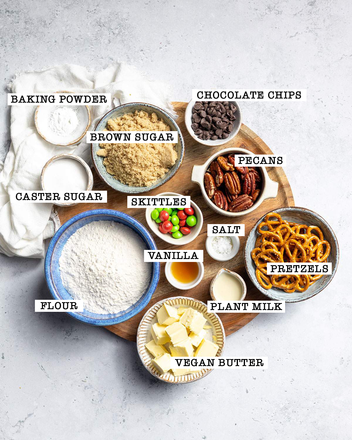 All ingredients for vegan kitchen sink cookies are sitting on round tray with labels next to each ingredient.