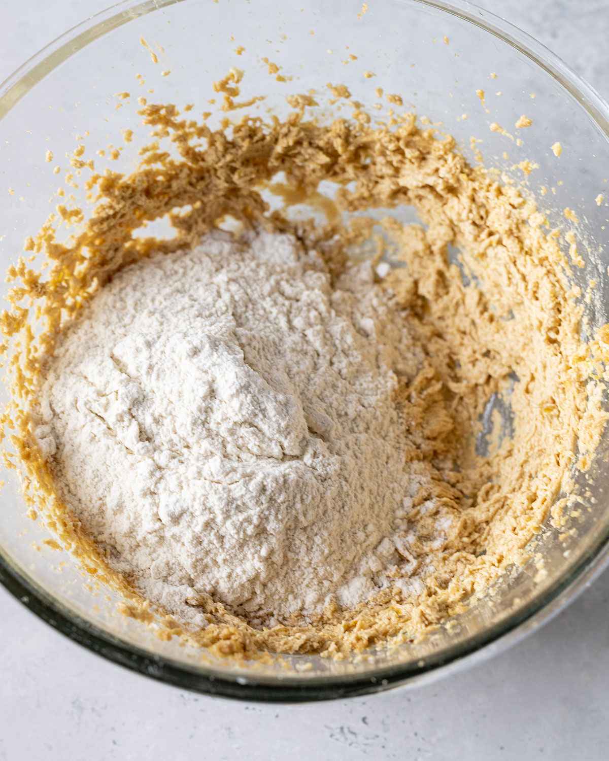 Dry ingredients for cookie dough added to creamed vegan butter and sugar in a mixing bowl.