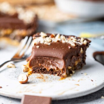 A slice of half-eaten decadent chocolate tart on a dessert plate.