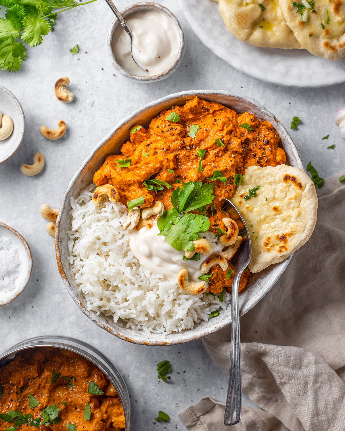 A serving plate with vegan tikka masala alongside basmati rice, fresh cilantro and naan bread on the side.