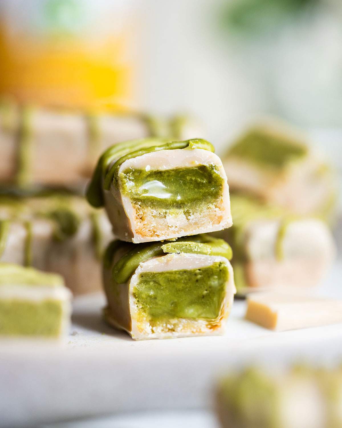 A white chocolate matcha twix bar is cut in half and the halves are stacked on top of each other with the green tea caramel visible inside the bar.