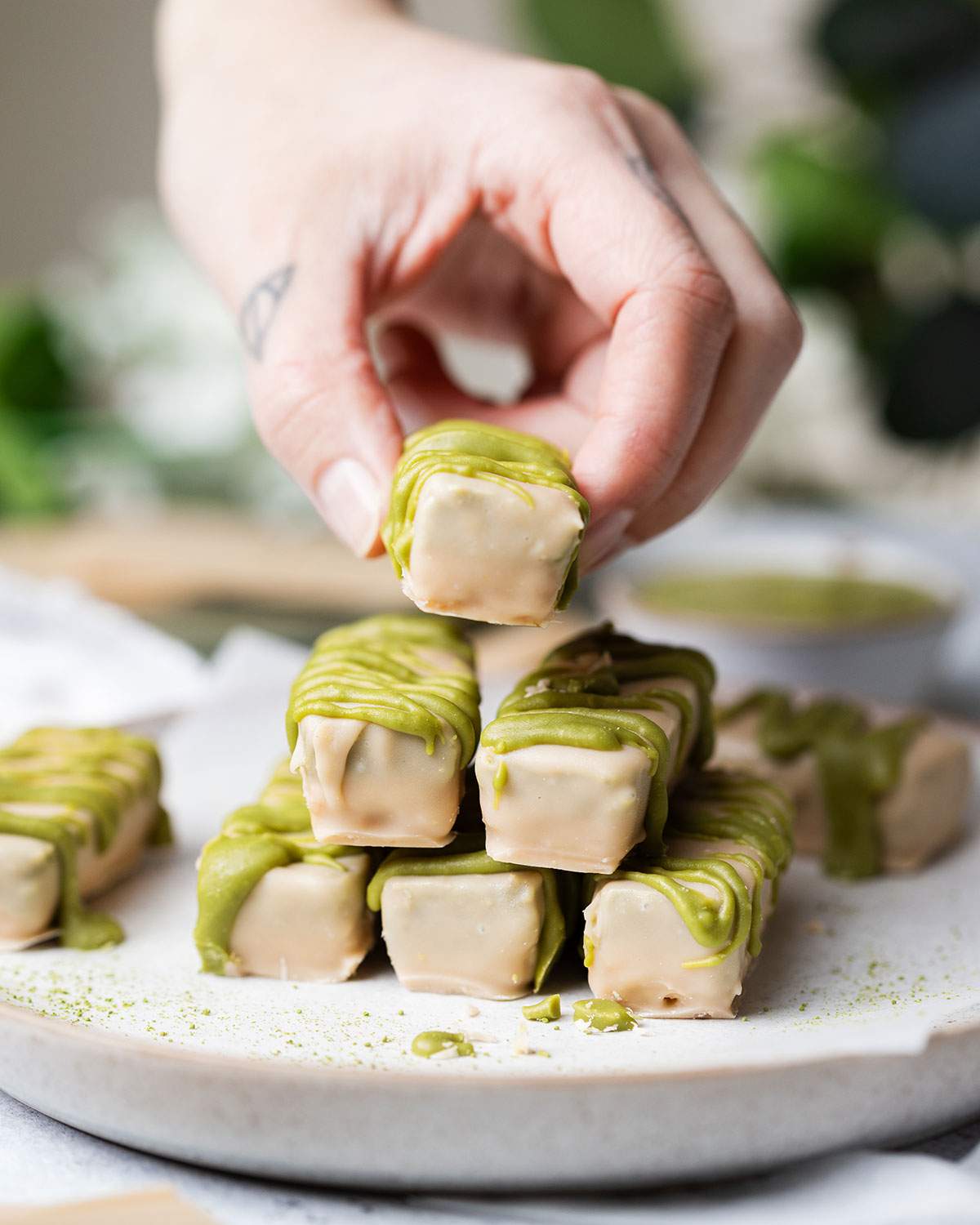 A hand is picking up a homemade matcha twix bars from a stack.