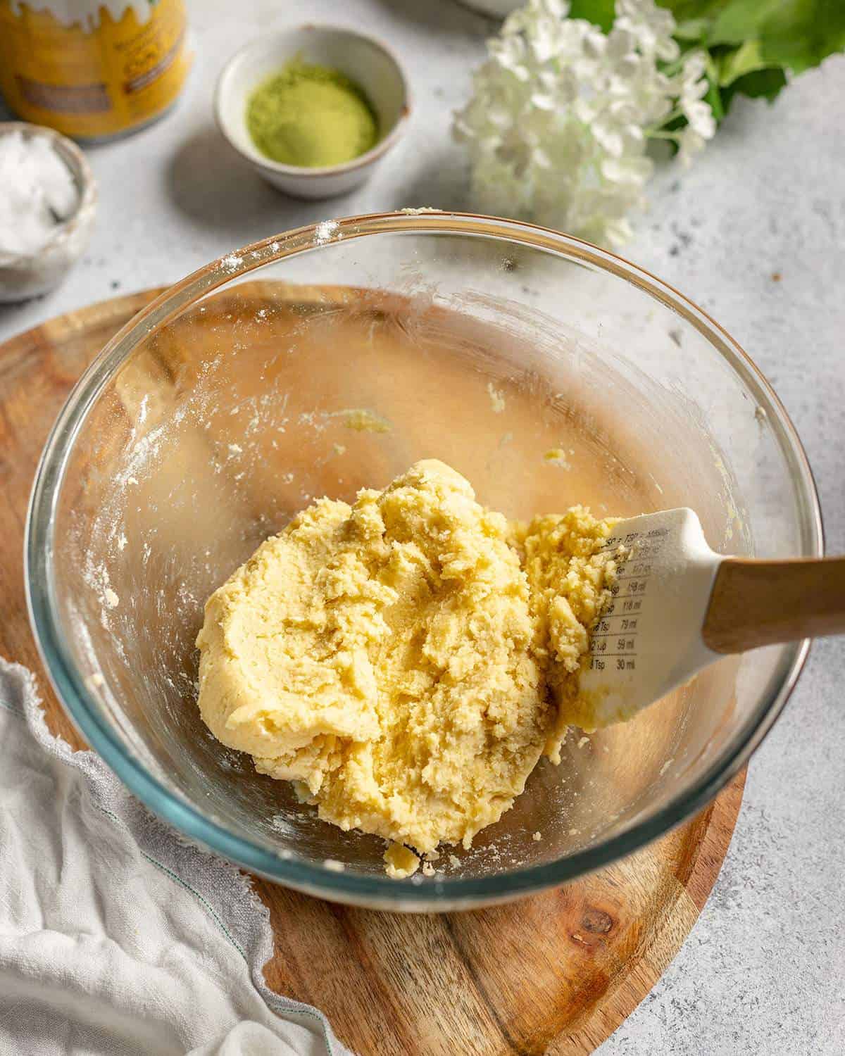 Vegan shortbread dough in a mixing bowl with a spatula on the side.