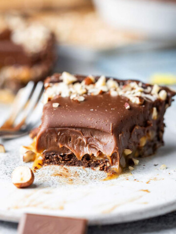 A slice of half-eaten decadent chocolate tart on a dessert plate.