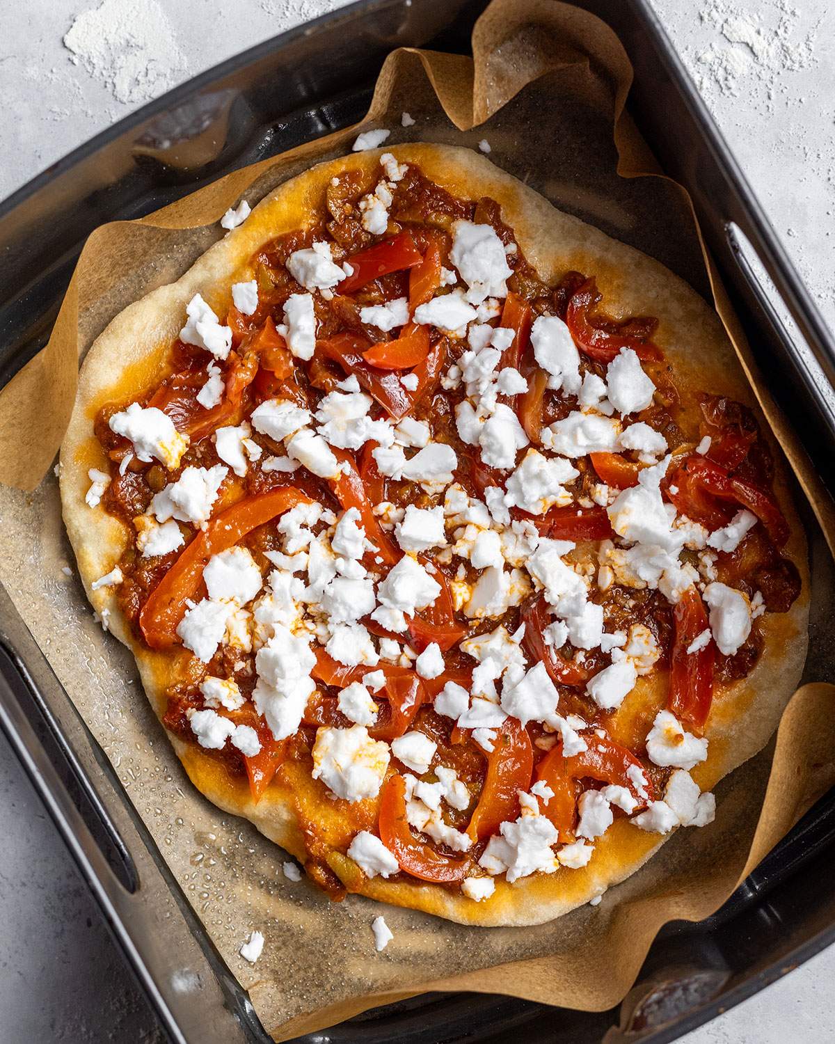 Flatbread pizza in air fryer basket before baking.