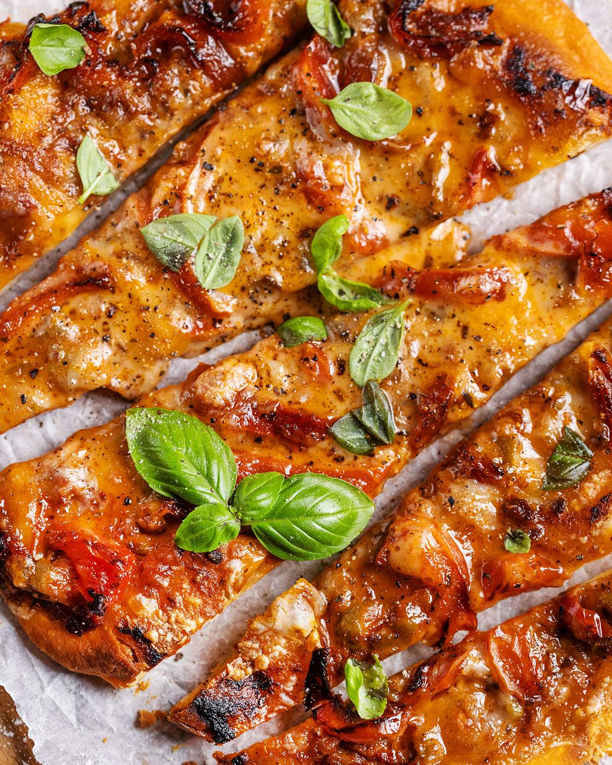 Air fryer flatbread pizza up close after slicing with fresh basil on top.