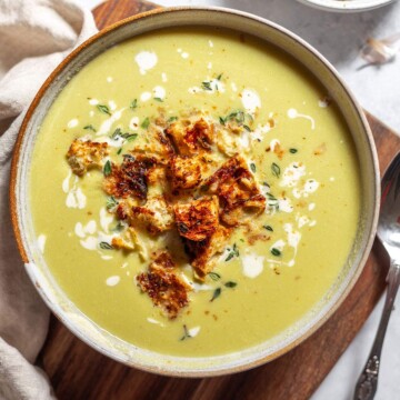 A bowl of green asparagus soup topped with homemade croutons.