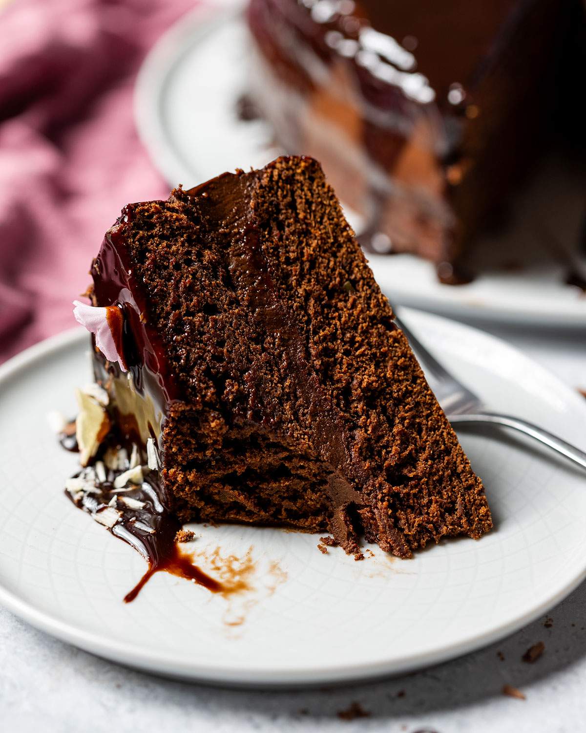 A slice of avocado chocolate cake on a small plate with a fork.