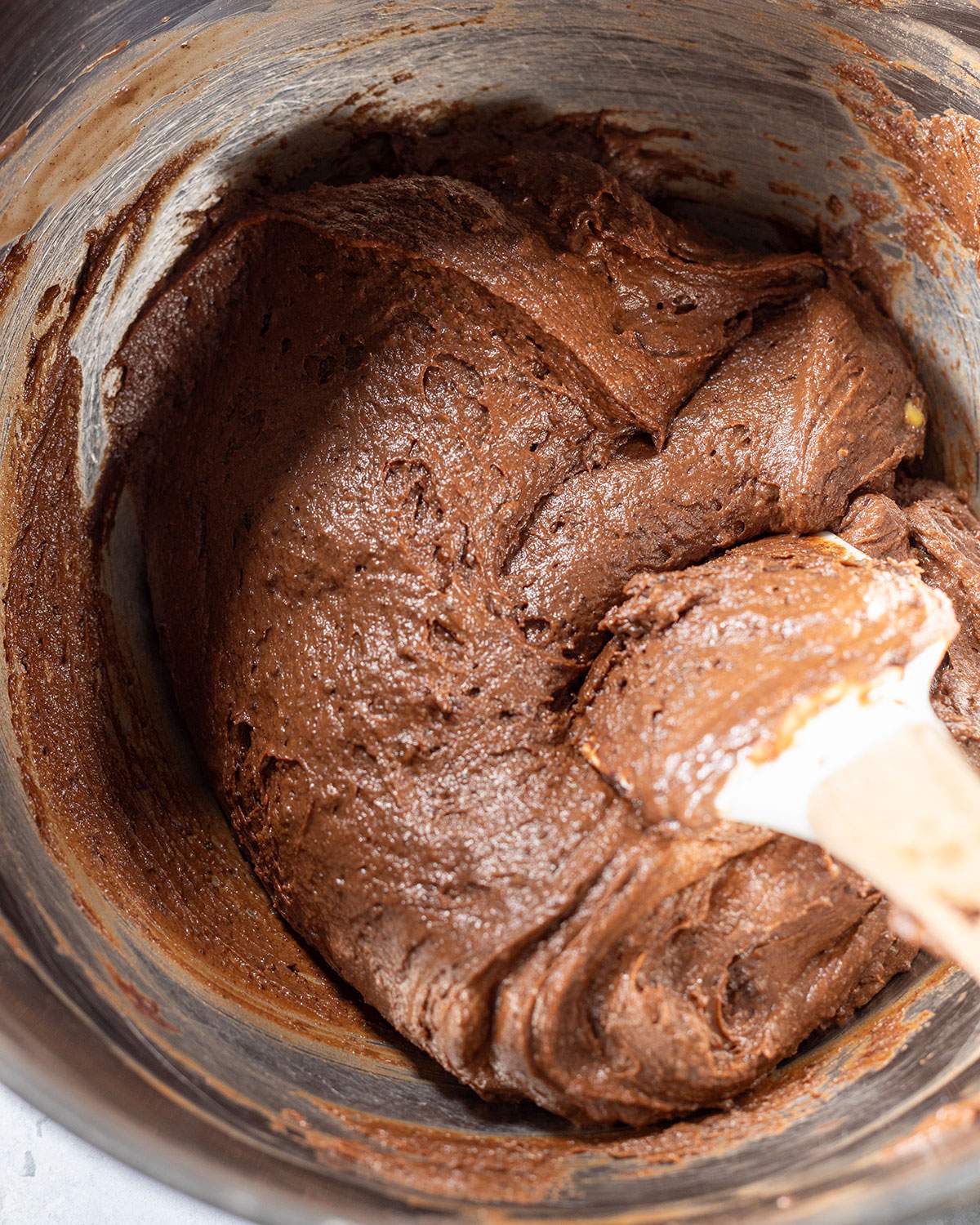 Avocado chocolate cake batter in a mixing bowl with a spatula.