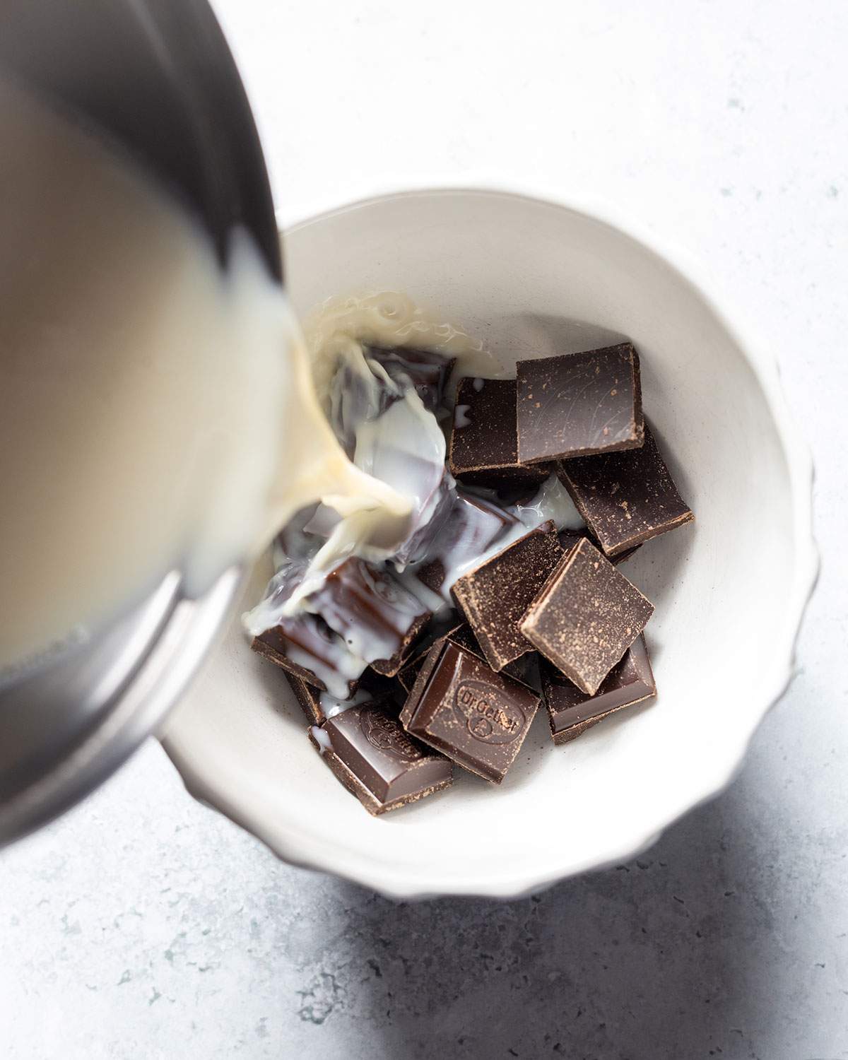 Pouring hot milk over chocolate to make ganache.