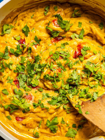 A creamy one pan orzo dish in a skillet with fresh herbs on top.