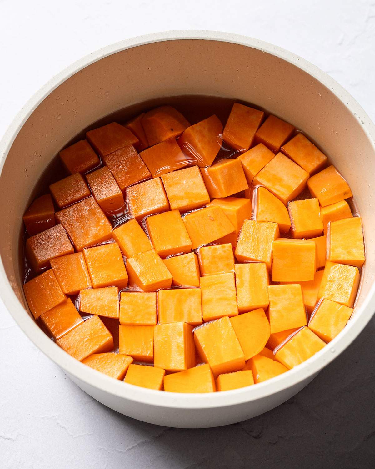 Sweet potato cubes in water in a saucepan.