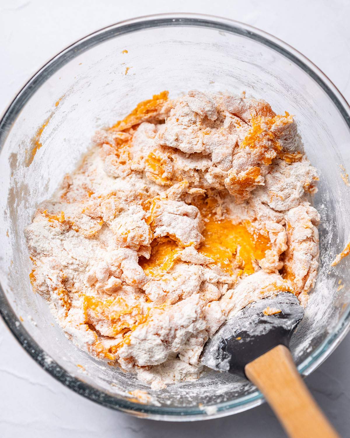 Sweet potato gnocchi dough being mixed in a glass bowl.