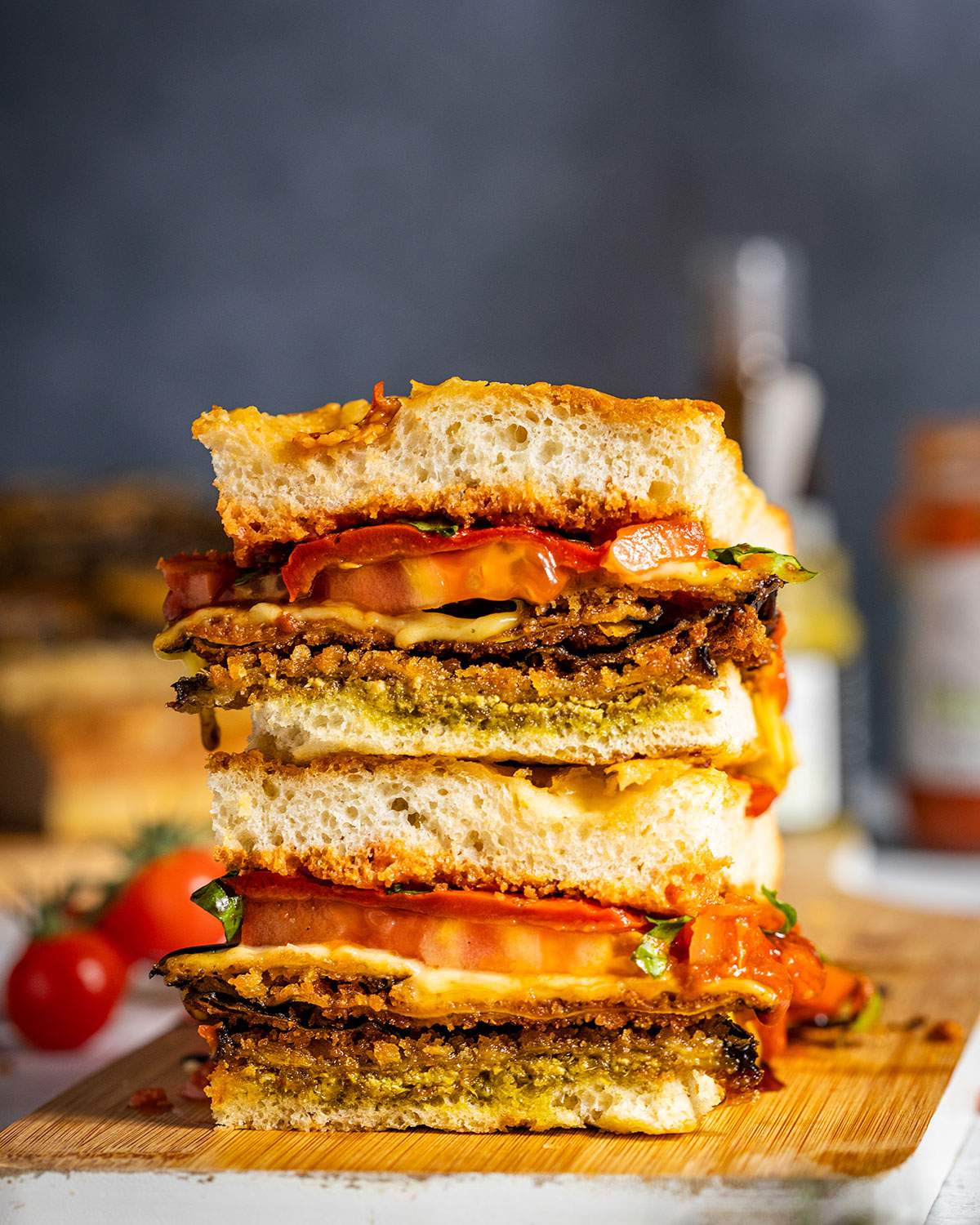 Two pieces of eggplant focaccia sandwich stacked on a serving board.