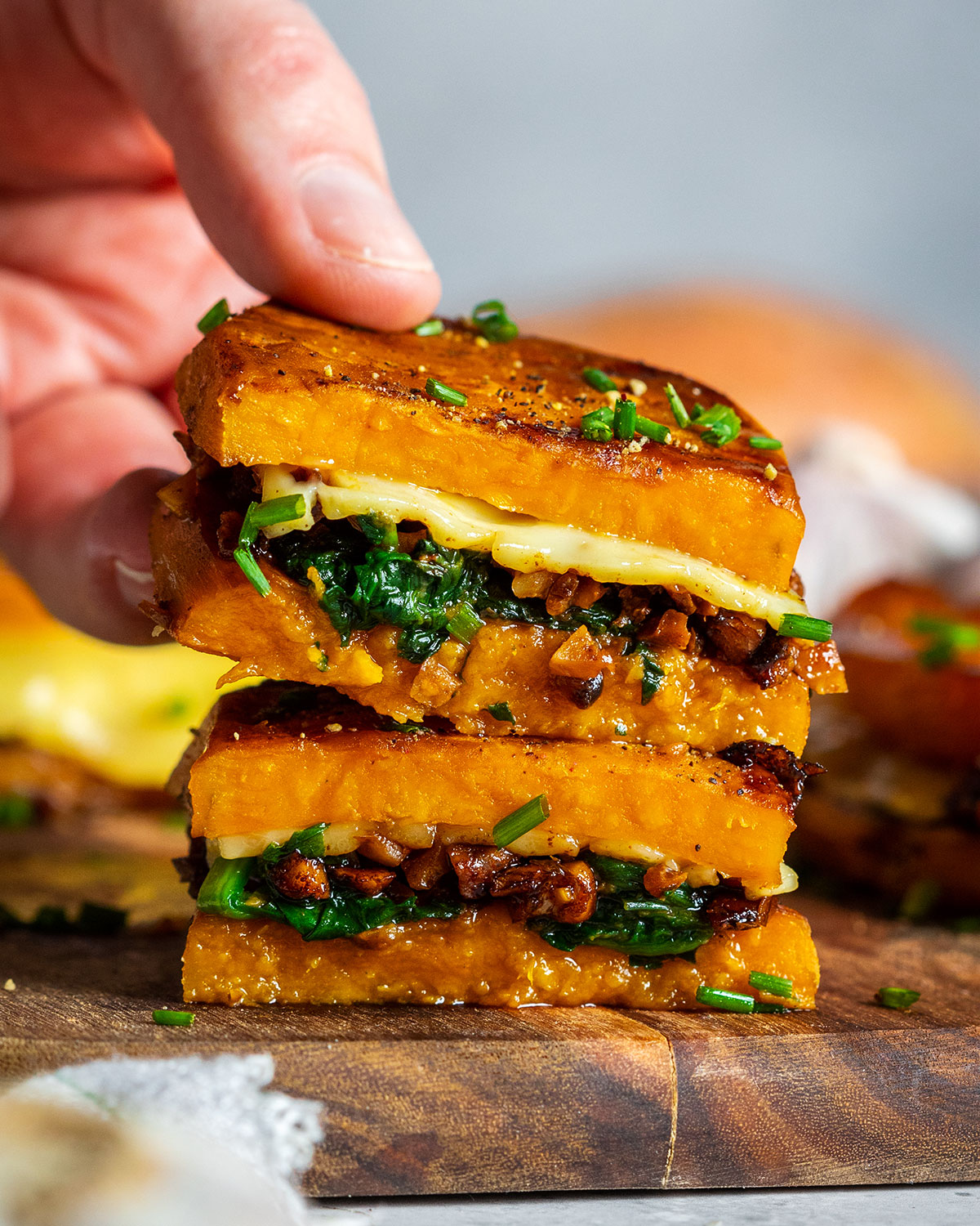 Stacked sweet potato grilled cheese sandwich and a hand picking up one.
