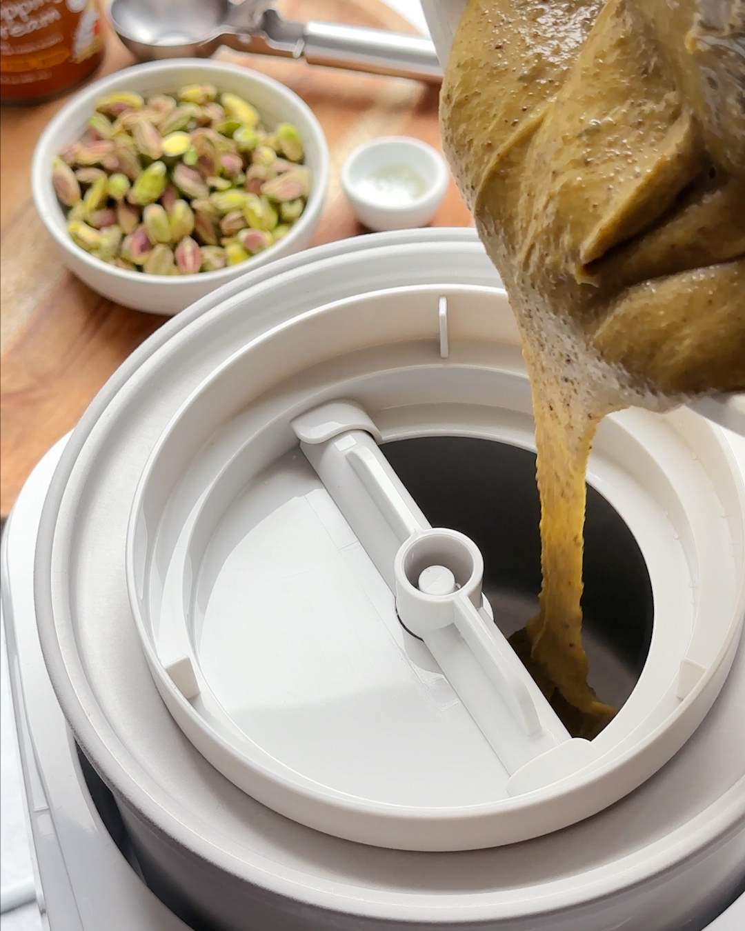 Pouring pistachio ice cream mix into an ice cream maker.