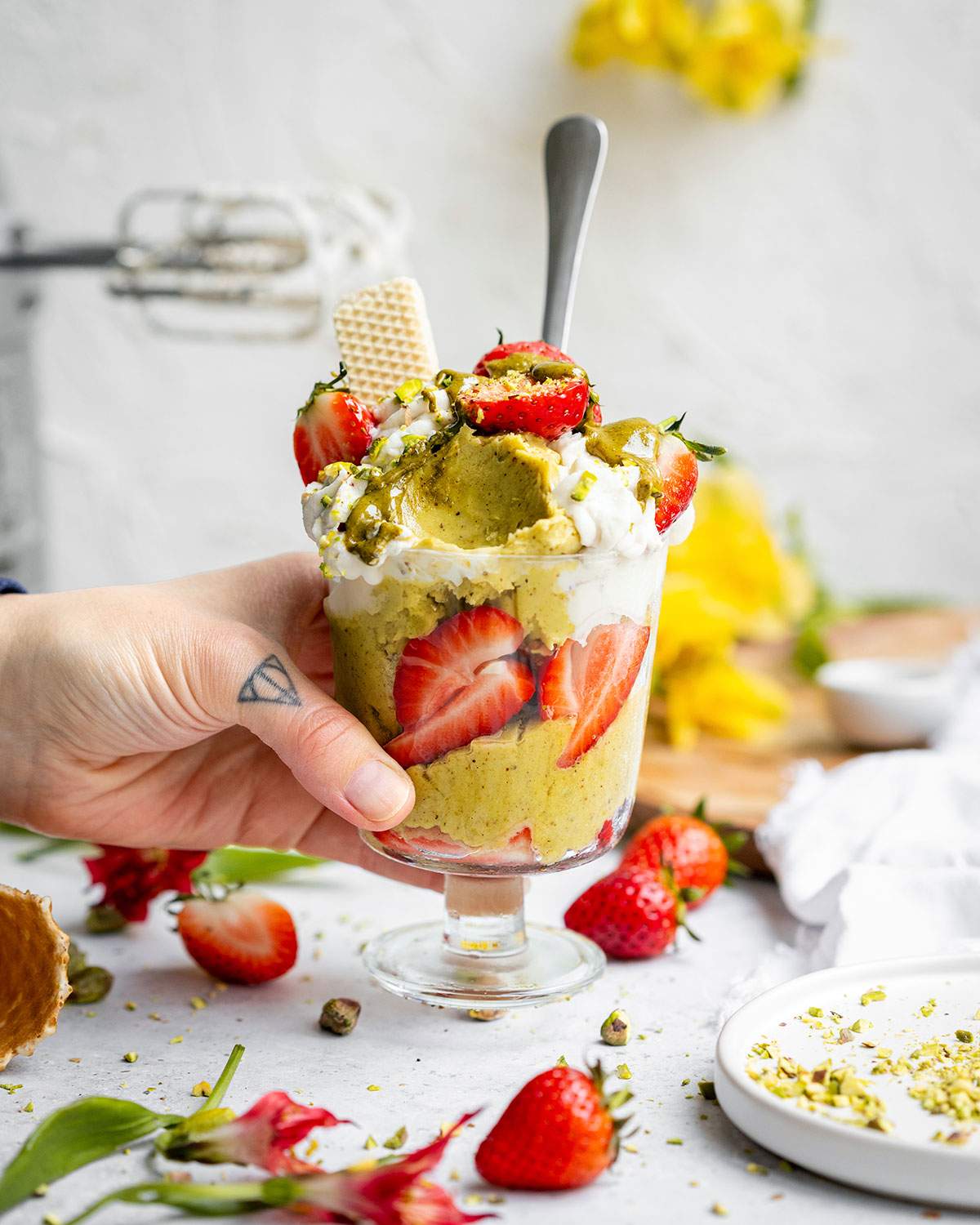 A hand picking up a jar of vegan pistachio ice cream.