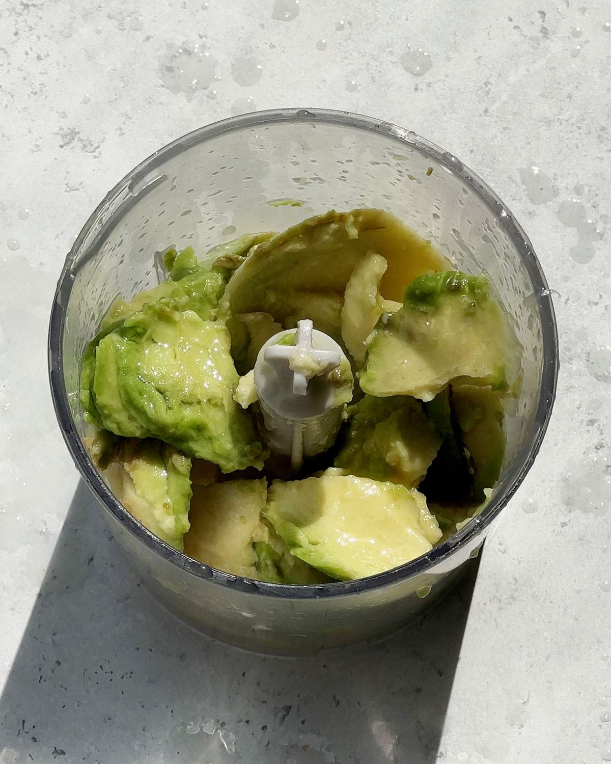 Avocado pieces in a blender bowl.