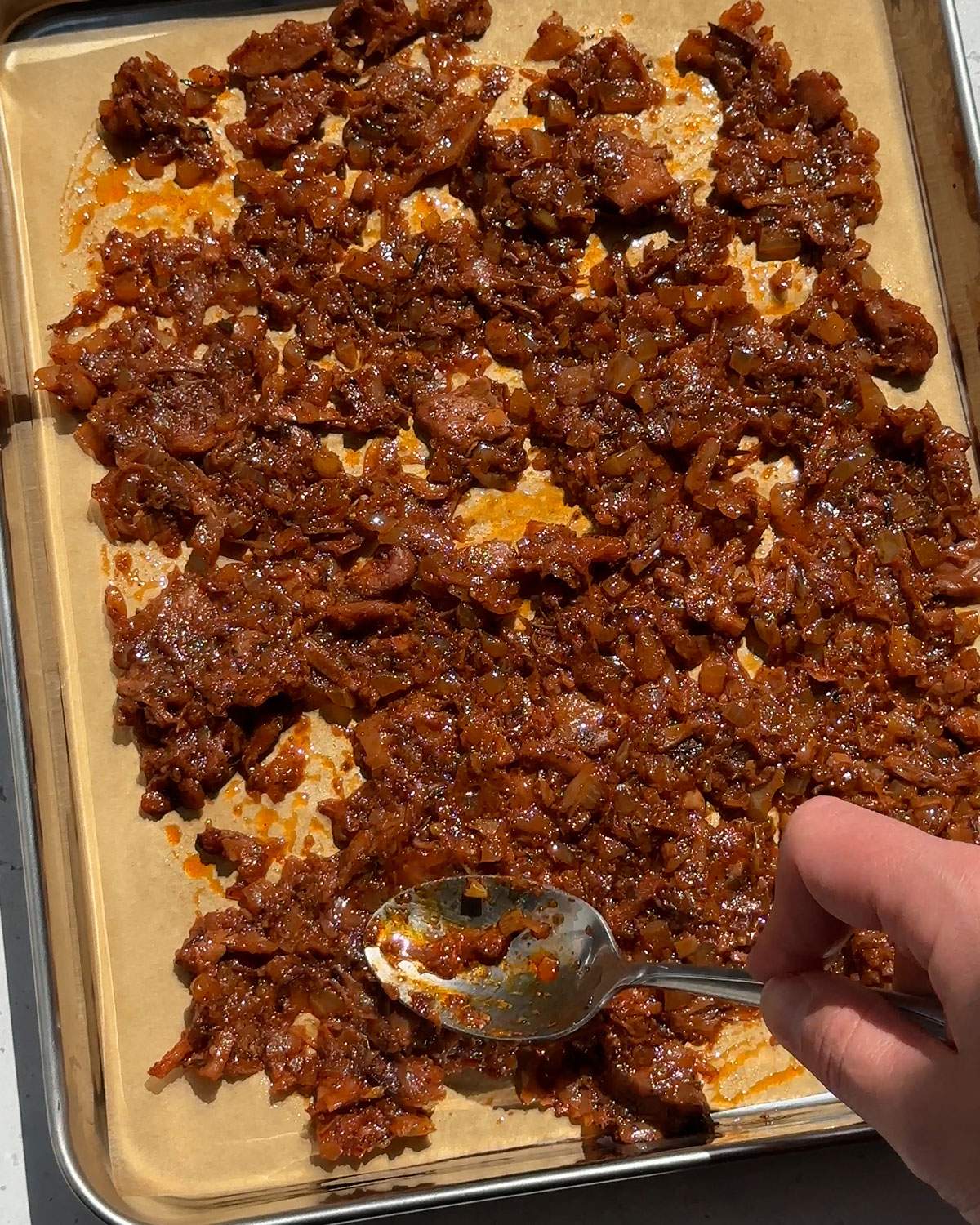 Spreading jackfruit carnitas on a baking tray.