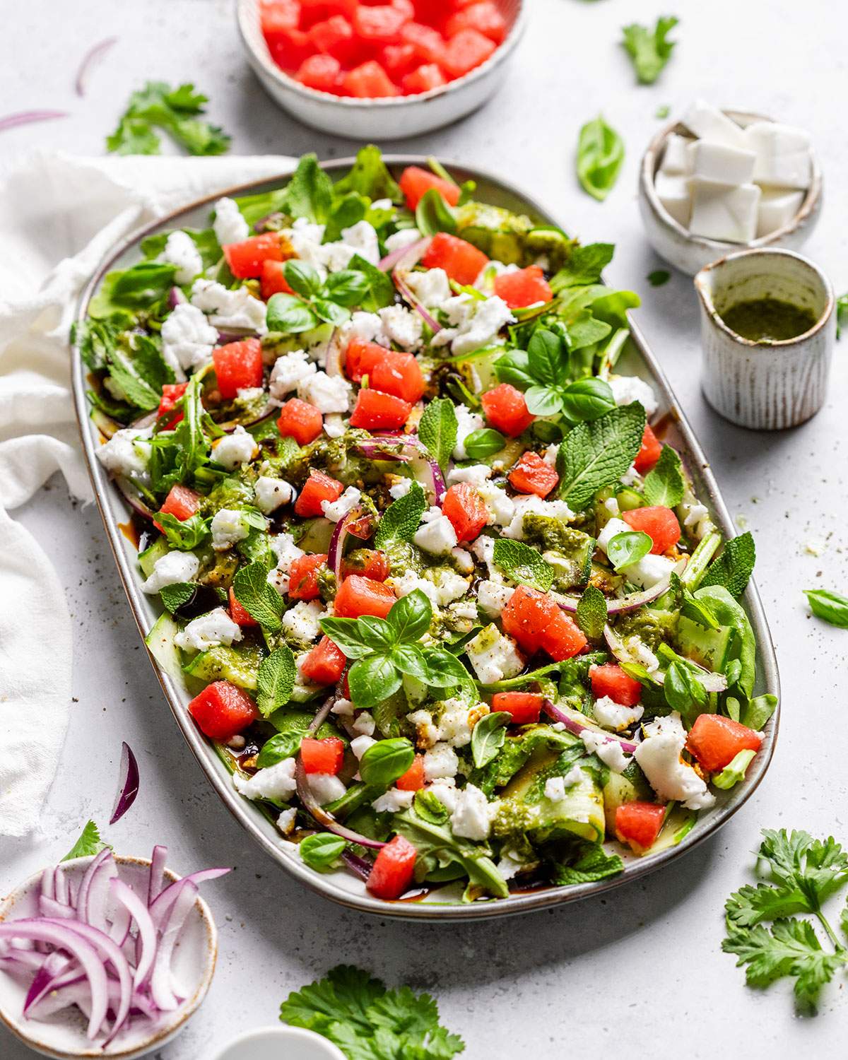 A platter with vibrant watermelon feta salad on a white table.