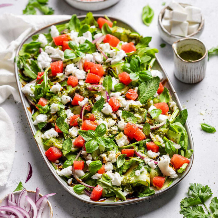 A platter with vibrant watermelon feta salad on a white table.