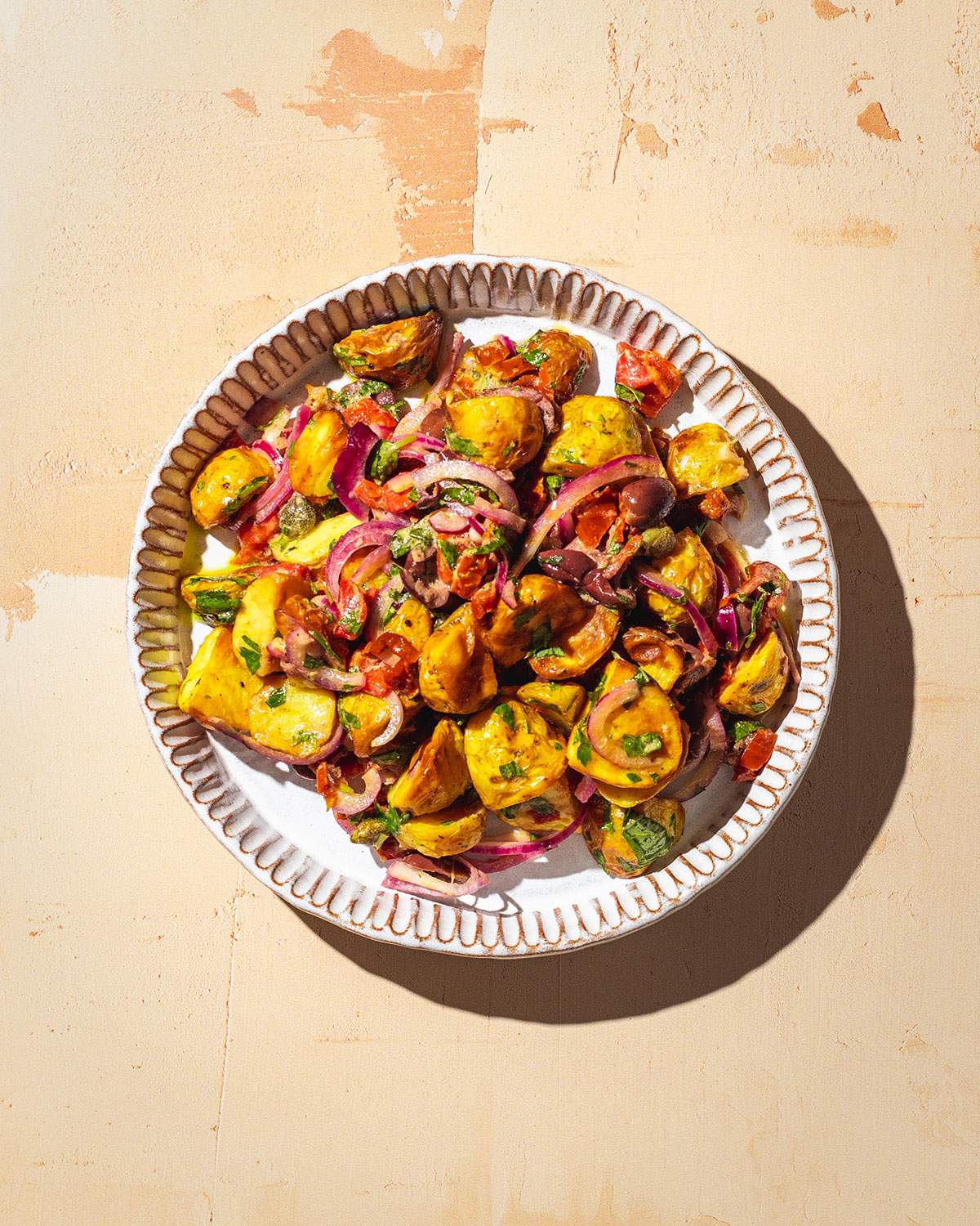 Italian potato salad on a serving plate in the sun.