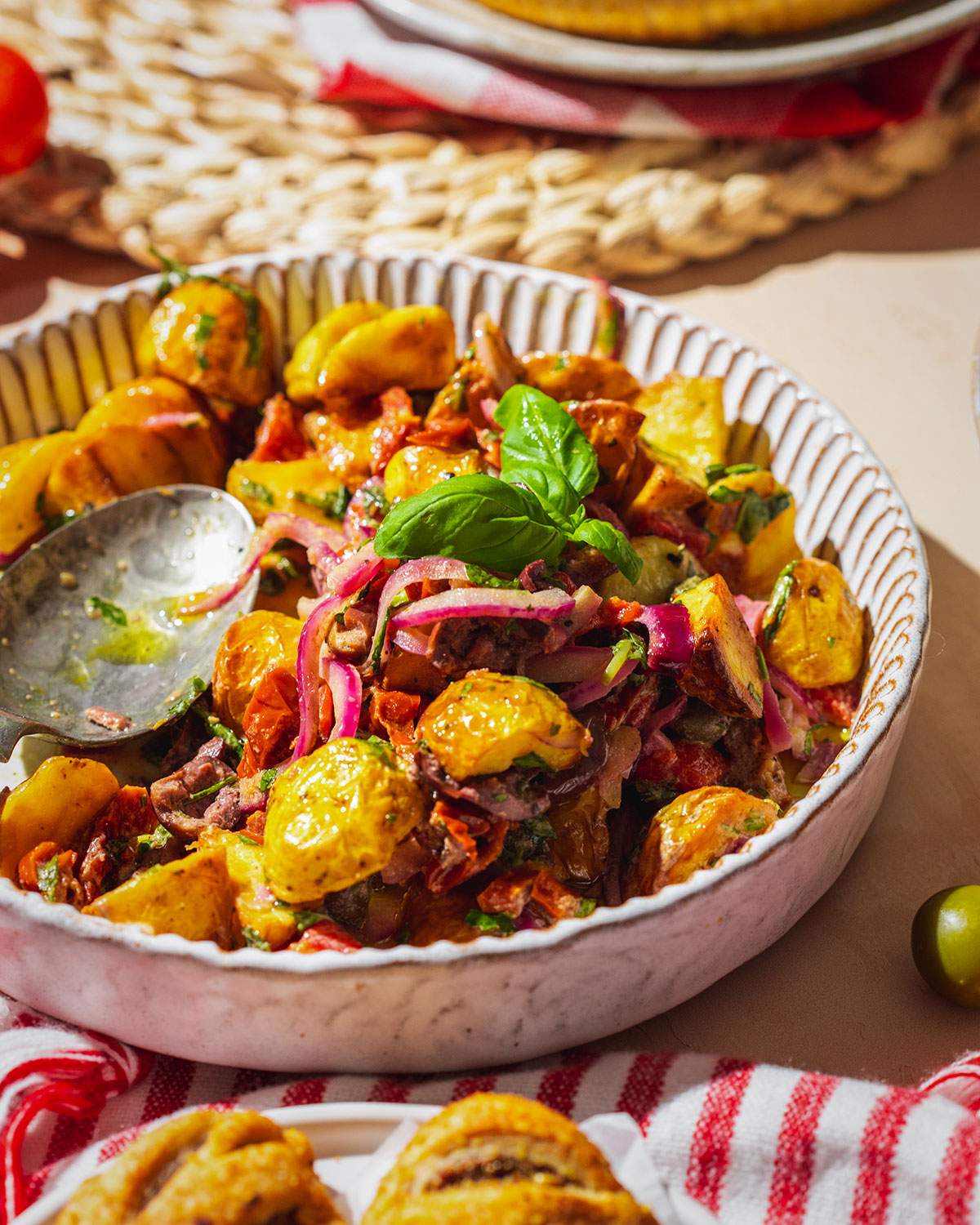 Italian potato salad in a bowl on top of a picnic table in the sun.