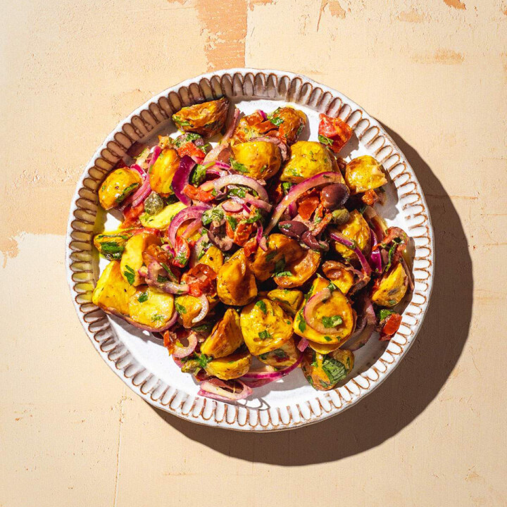 Italian potato salad on a serving plate in the sun.
