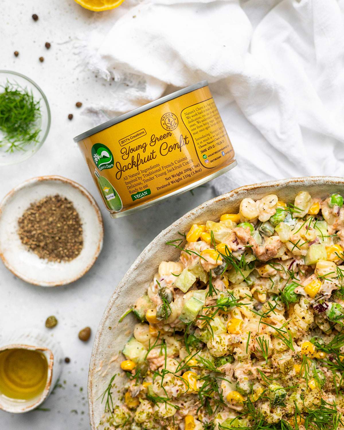 A tin of jackfruit confit next to a bowl of vegan tuna pasta salad.