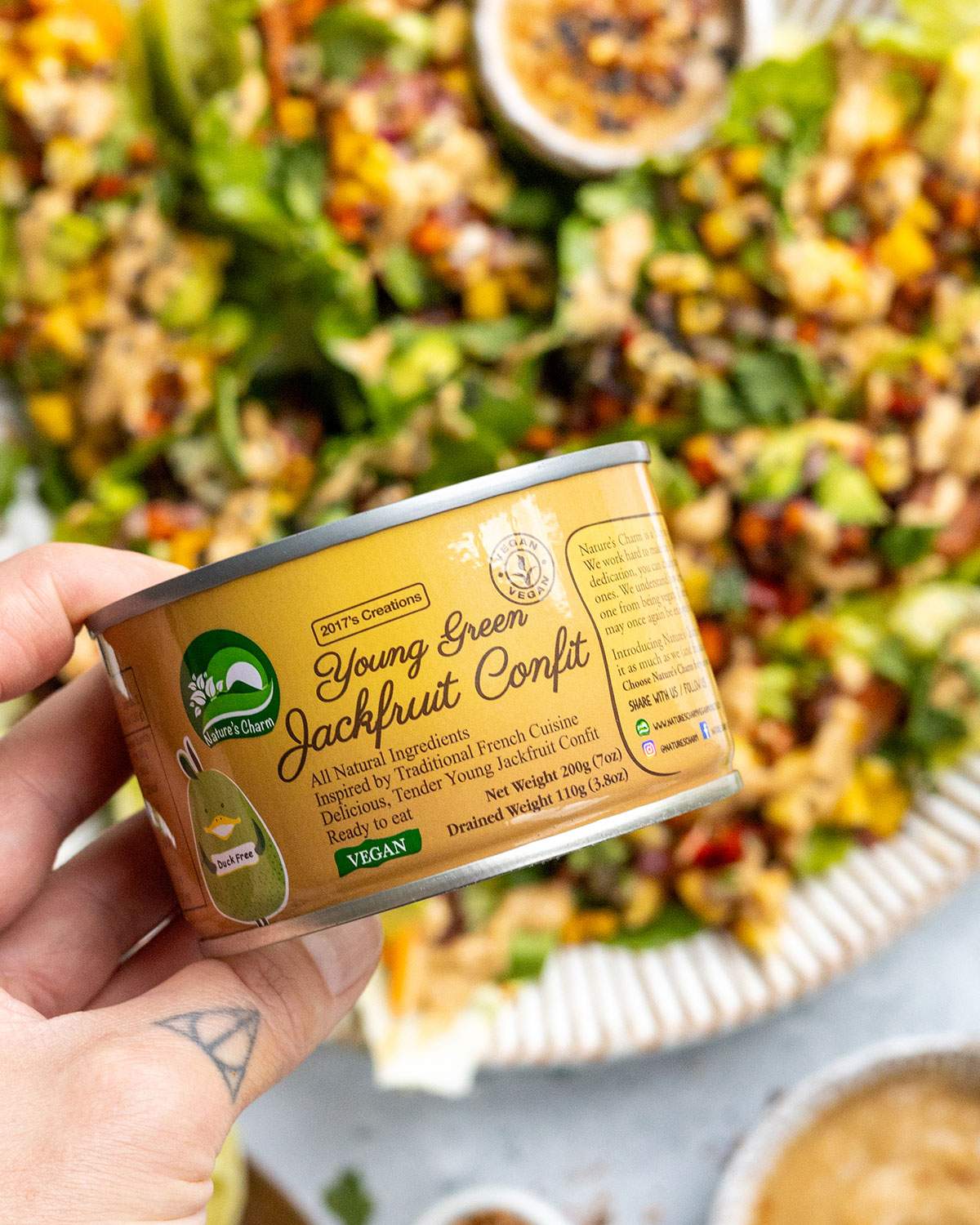 A hand holding a tin of jackfruit confit.