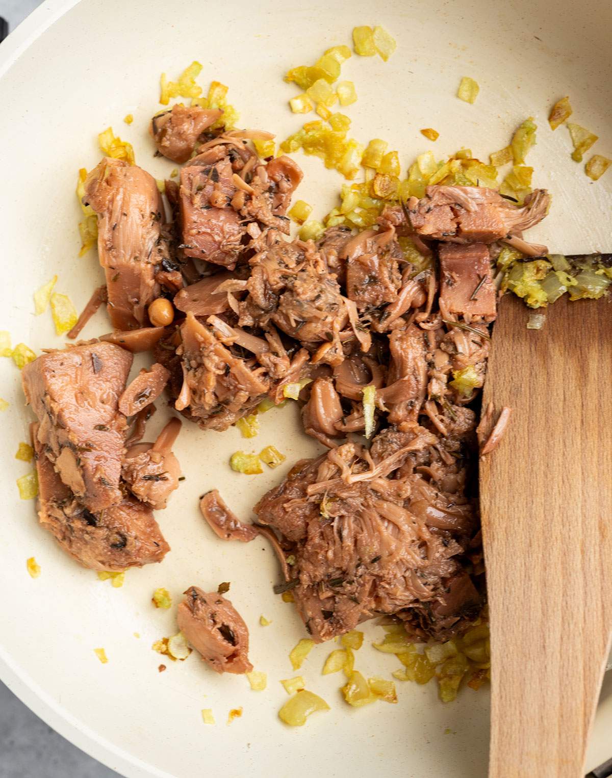 Jackfruit confit added to onion and garlic in a skillet.