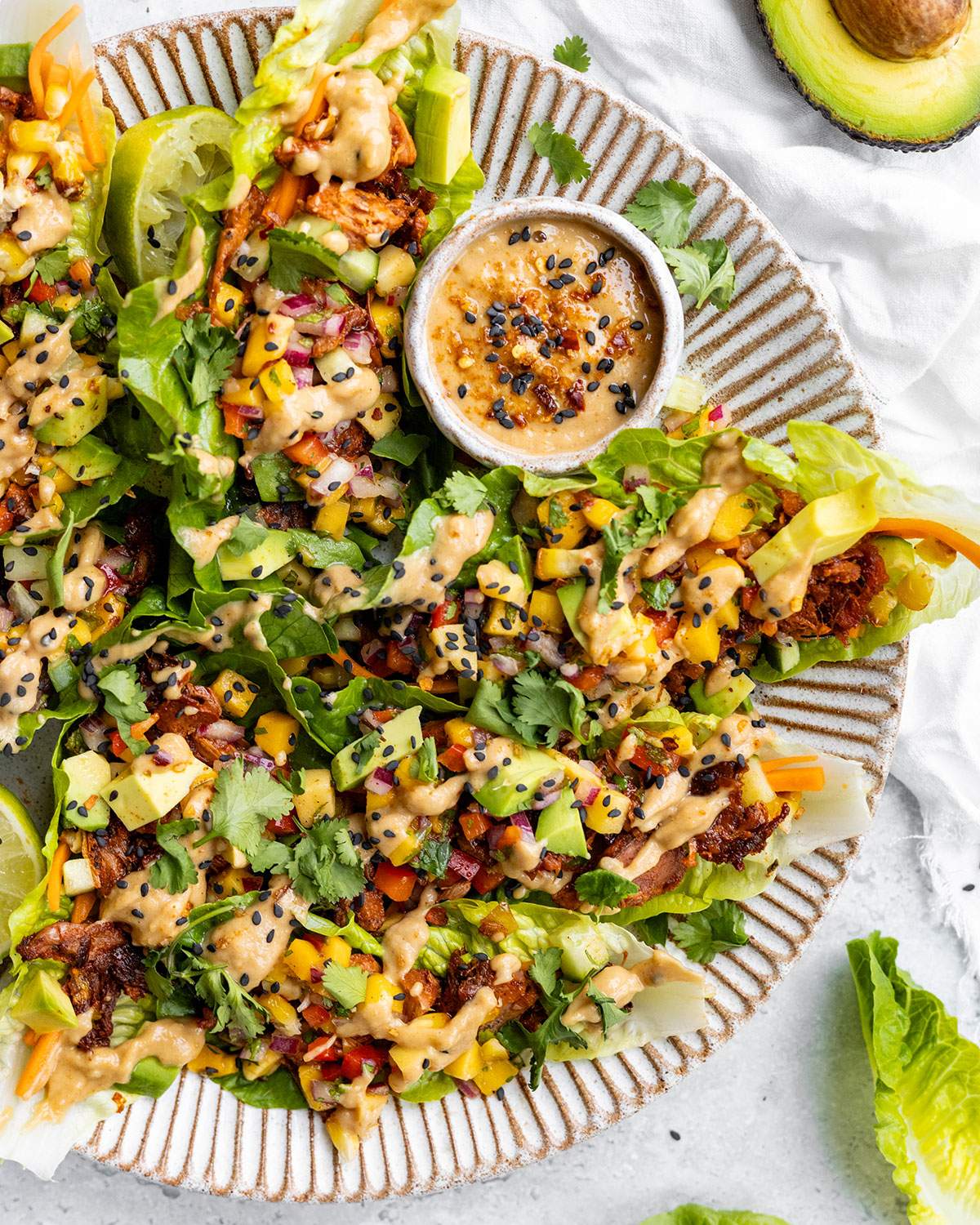Spicy jackfruit lettuce wraps drizzled with tangy peanut sauce on a serving platter.