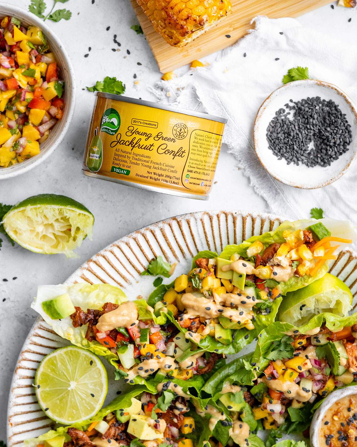 A tin of young green jackfruit confit next to a platter with lettuce wraps.