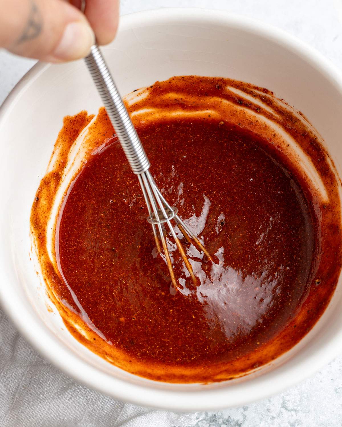 Whisking sriracha sauce in a small bowl.