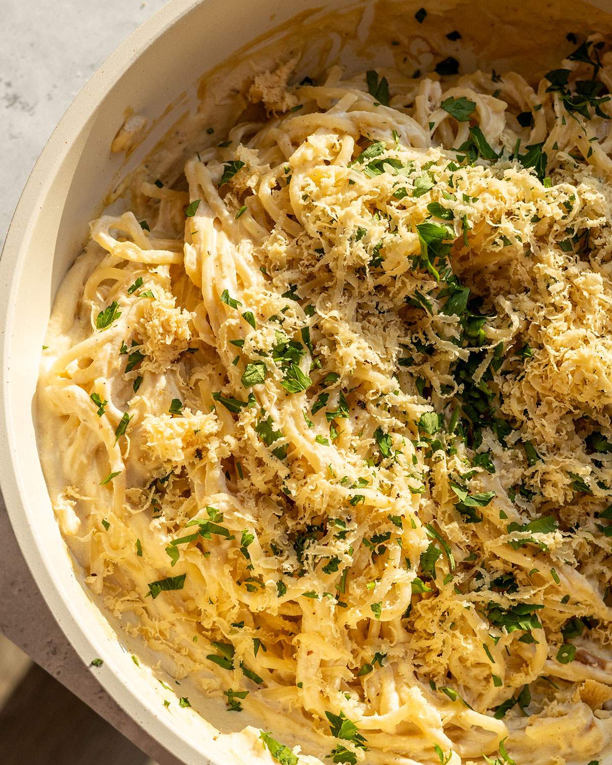 Grated vegan parmesan on a creamy pasta dish.