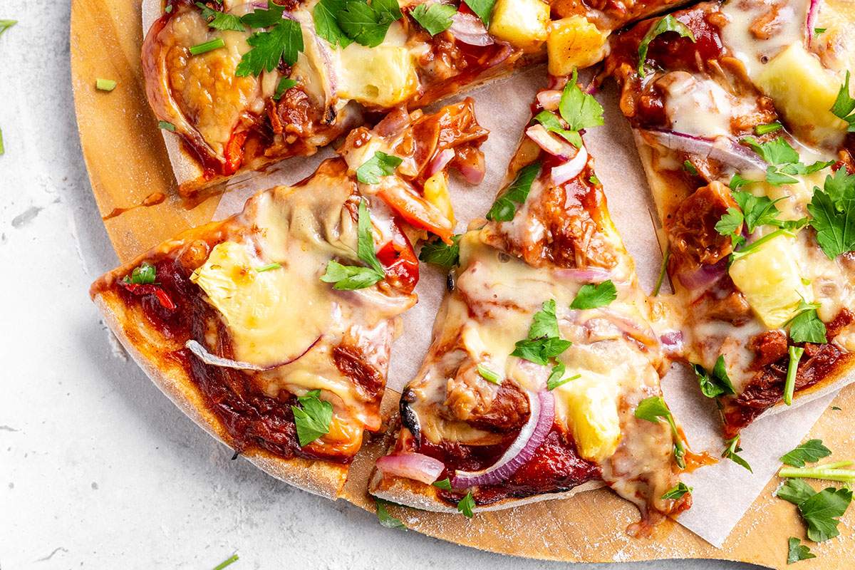 Slices of vegan BBQ pizza on a serving board.