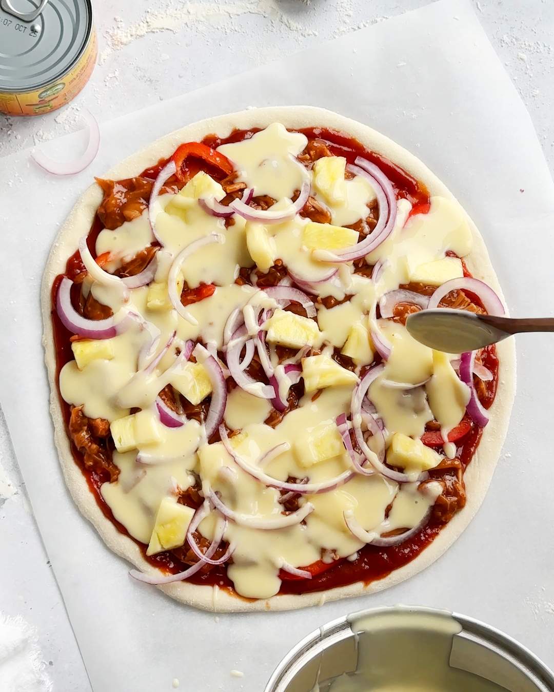 Adding vegan cheese sauce onto pizza.