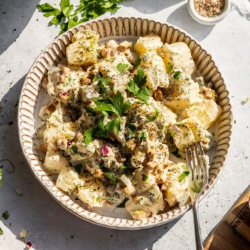A plate filled with creamy vegan potato salad on the dinner table.