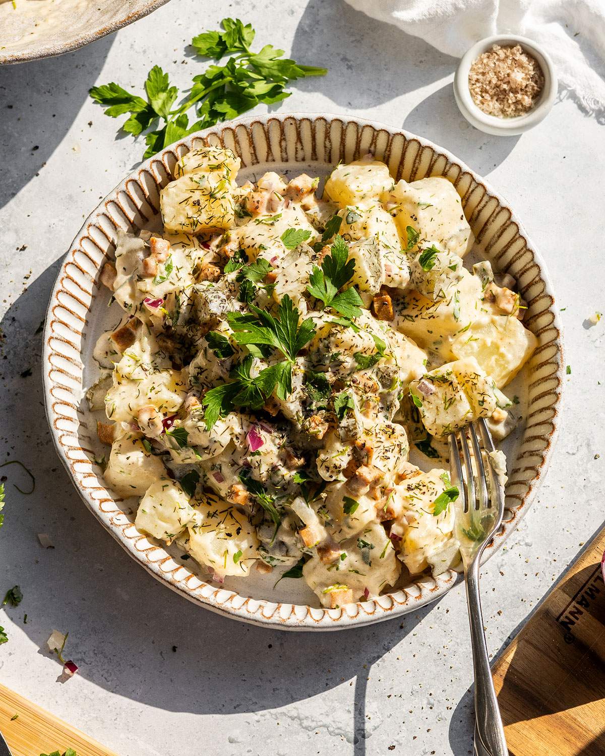 A plate filled with creamy vegan potato salad on the dinner table.