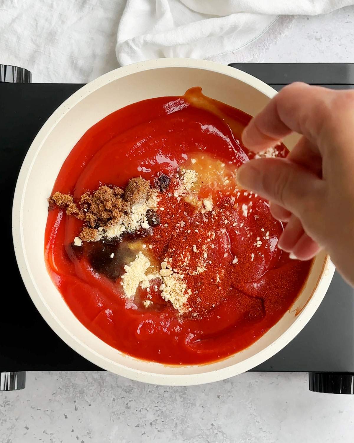 Adding seasonings to ketchup in a pan.