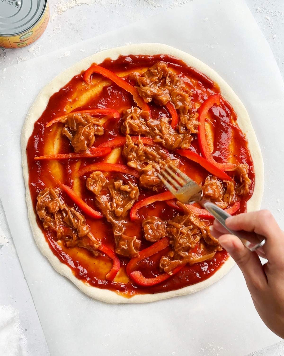Adding bbq jackfruit onto pizza.