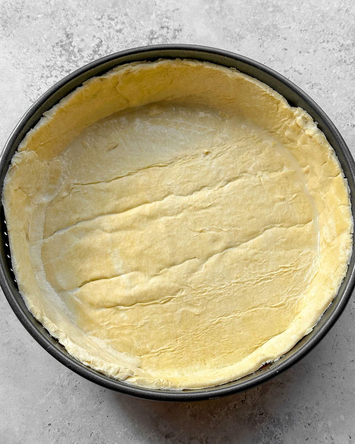Trimmed puff pastry bottom in a pie pan.