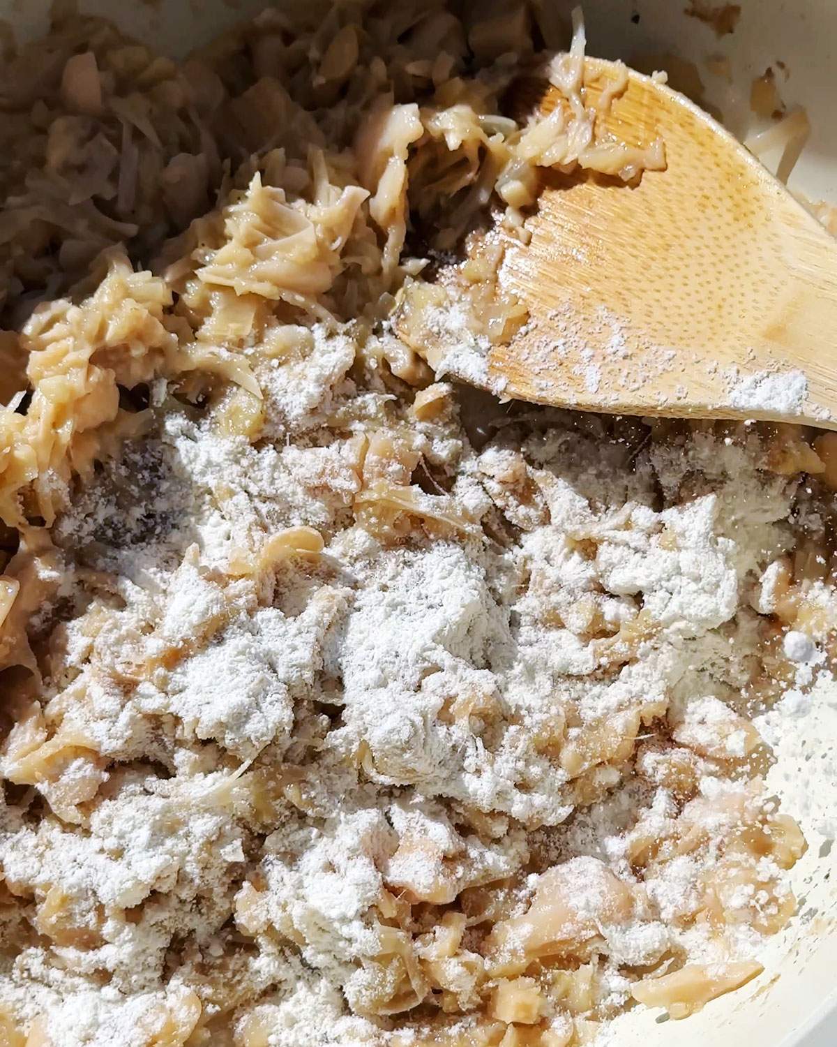 Flour sprinkled on top of jackfruit in skillet.