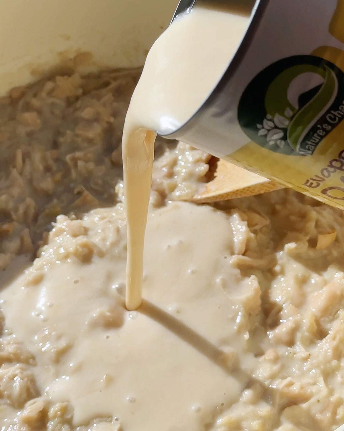 Pouring evaporated milk into a skillet.
