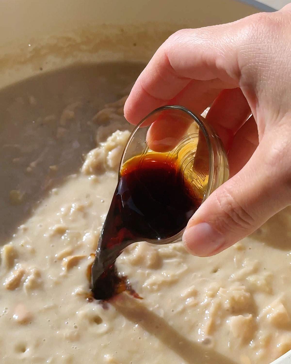 Pouring tamari soy sauce into skillet.