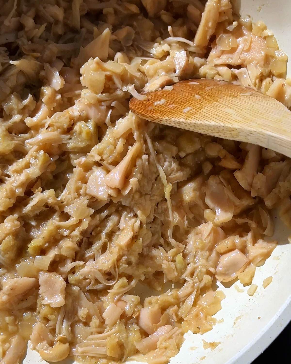 Stirring shredded jackfruit in a skillet.
