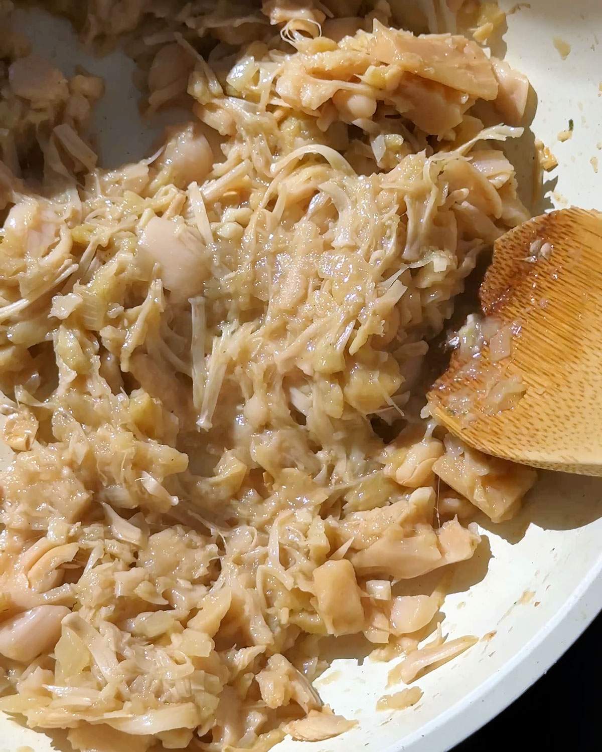 Stirring shredded jackfruit in a skillet.