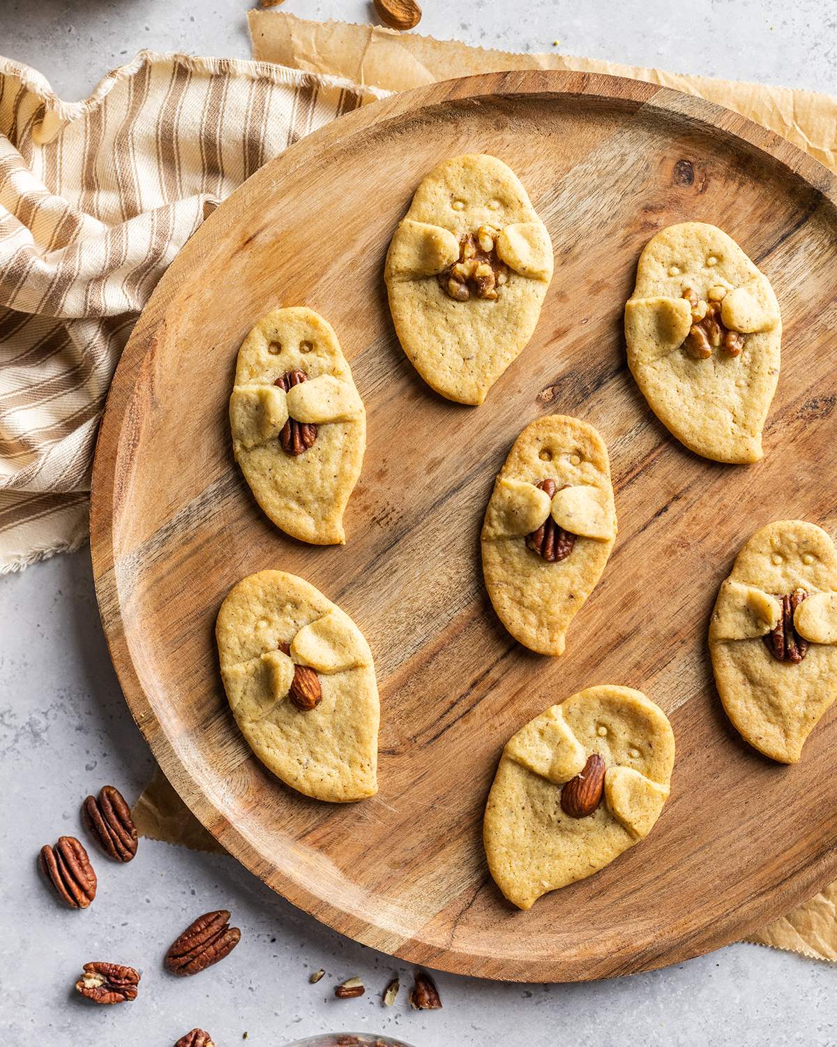Cute ghost shaped cookies on a wooden platter.