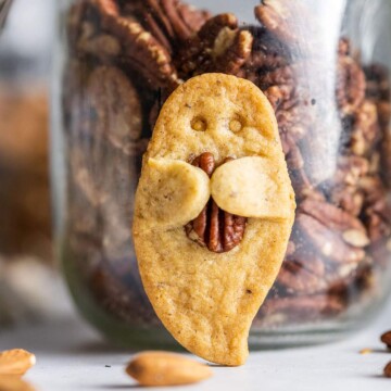 Up close, a ghost-shaped cookie holding a pecan nut.