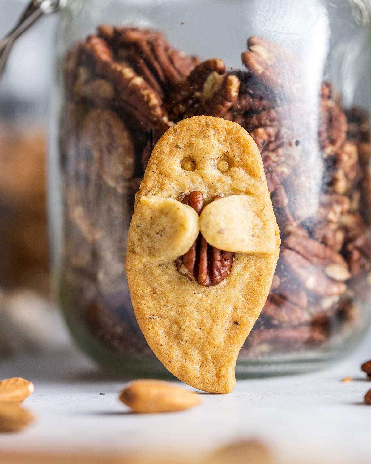 Up close, a ghost-shaped cookie holding a pecan nut.